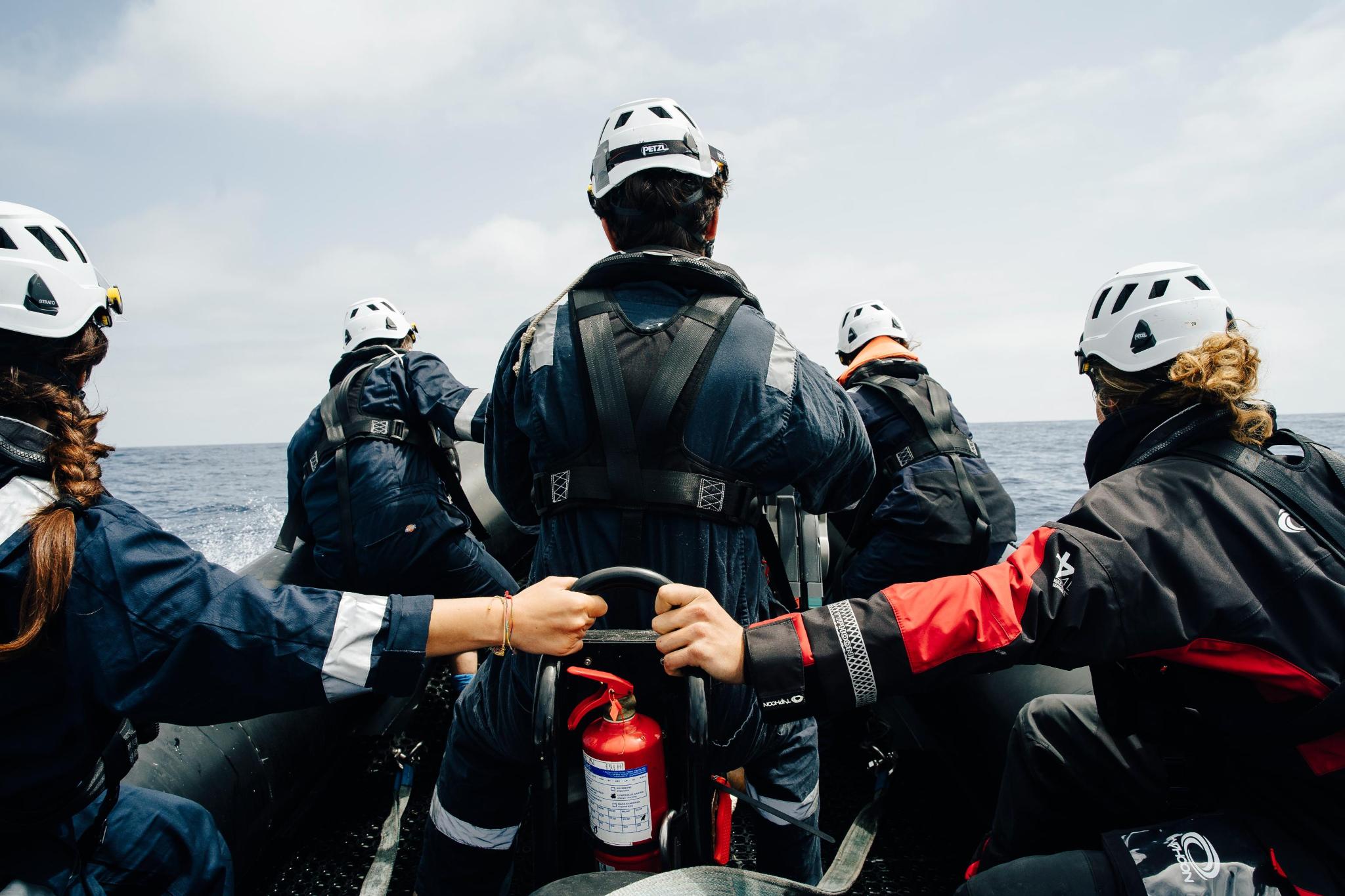 Justice Fleet Ein Foto von fünf Personen, die von hinten zu sehen sind, während sie in einem RHIB-Boot auf dem Meer fahren.