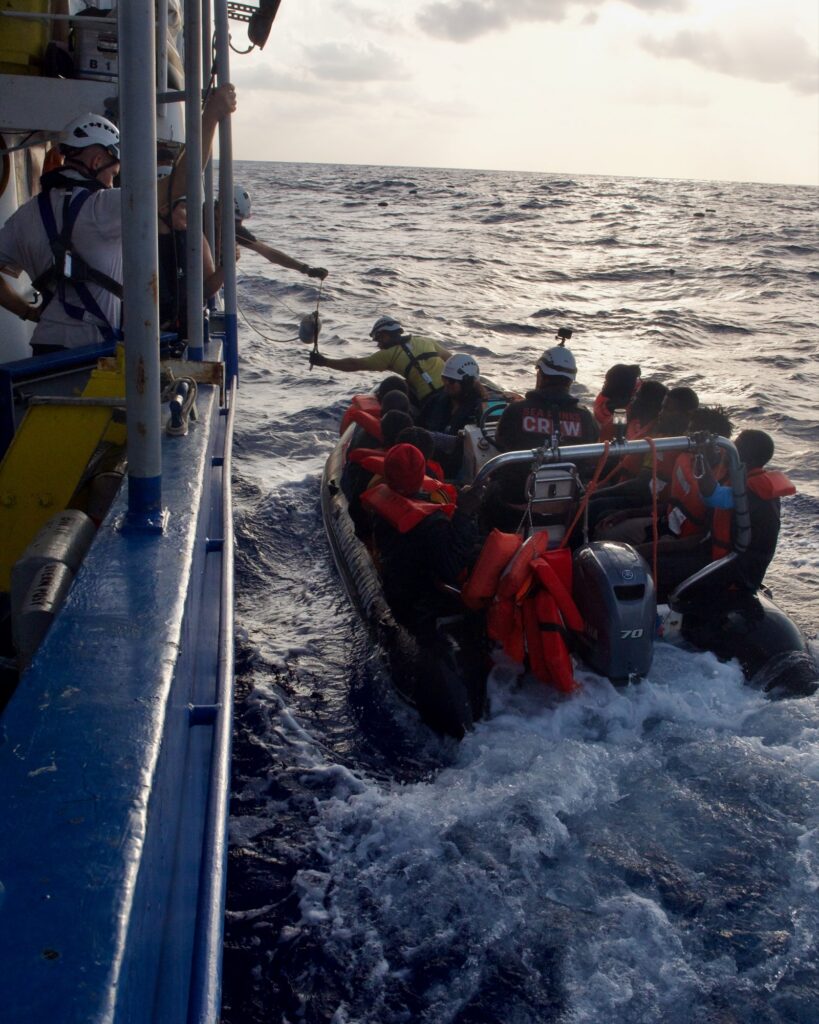 Rescued people in life jackets being brought aboard Sea Punk I from the rescue boat