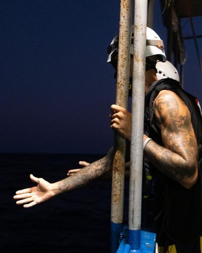 a crew member of Sea Punk I gives a hand to embark survivors