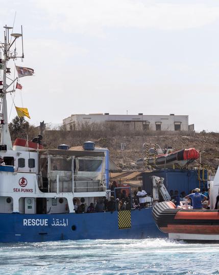 Sea Punk disembarking survivors in Lampedusa, also a ship of the Italian coast guard
