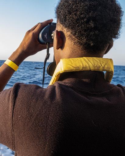 a survivor looking with binoculars at the sea