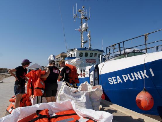 Crew members sort and stow life jackes on Sea Punk I