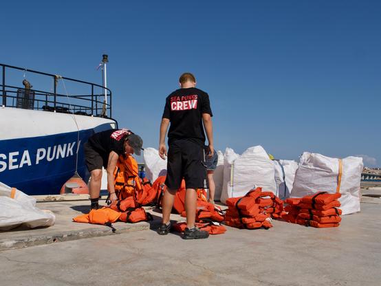 Crew members sort and stow life jackes on Sea Punk I